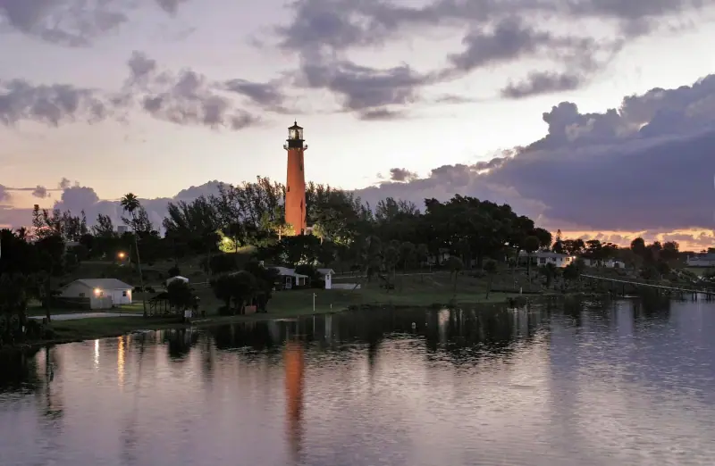 The red Jupiter Inlet Lighthouse at dusk, reflected in the water